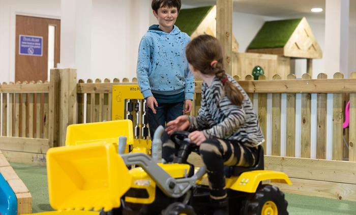 kids playing on tractors in play barn